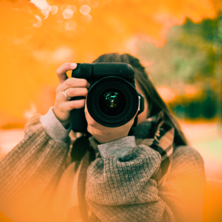 Das Bild zeigt eine Frau, die gerade mit einer professionellen Spiegelreflexkamera fotografiert.